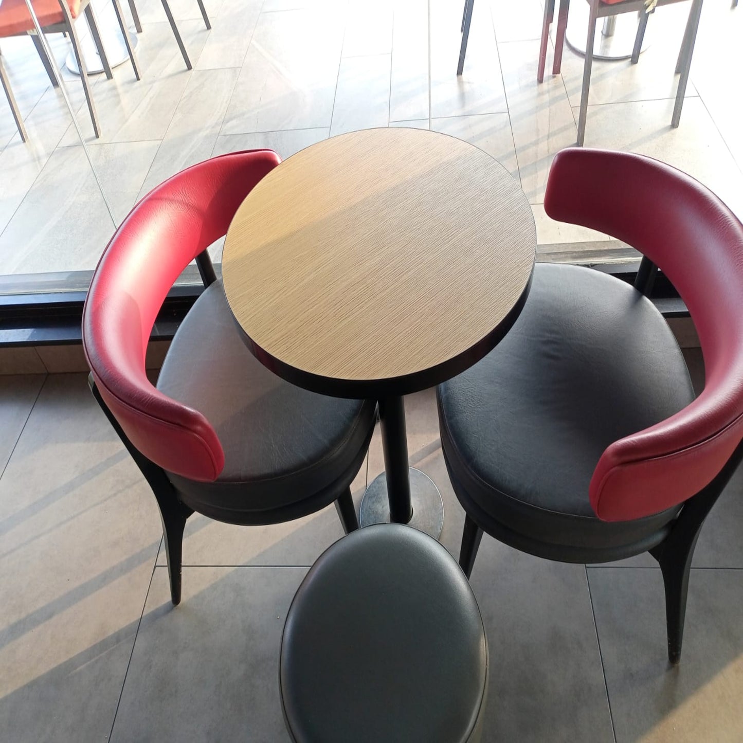 Round wooden table with red and black chairs in a modern setting