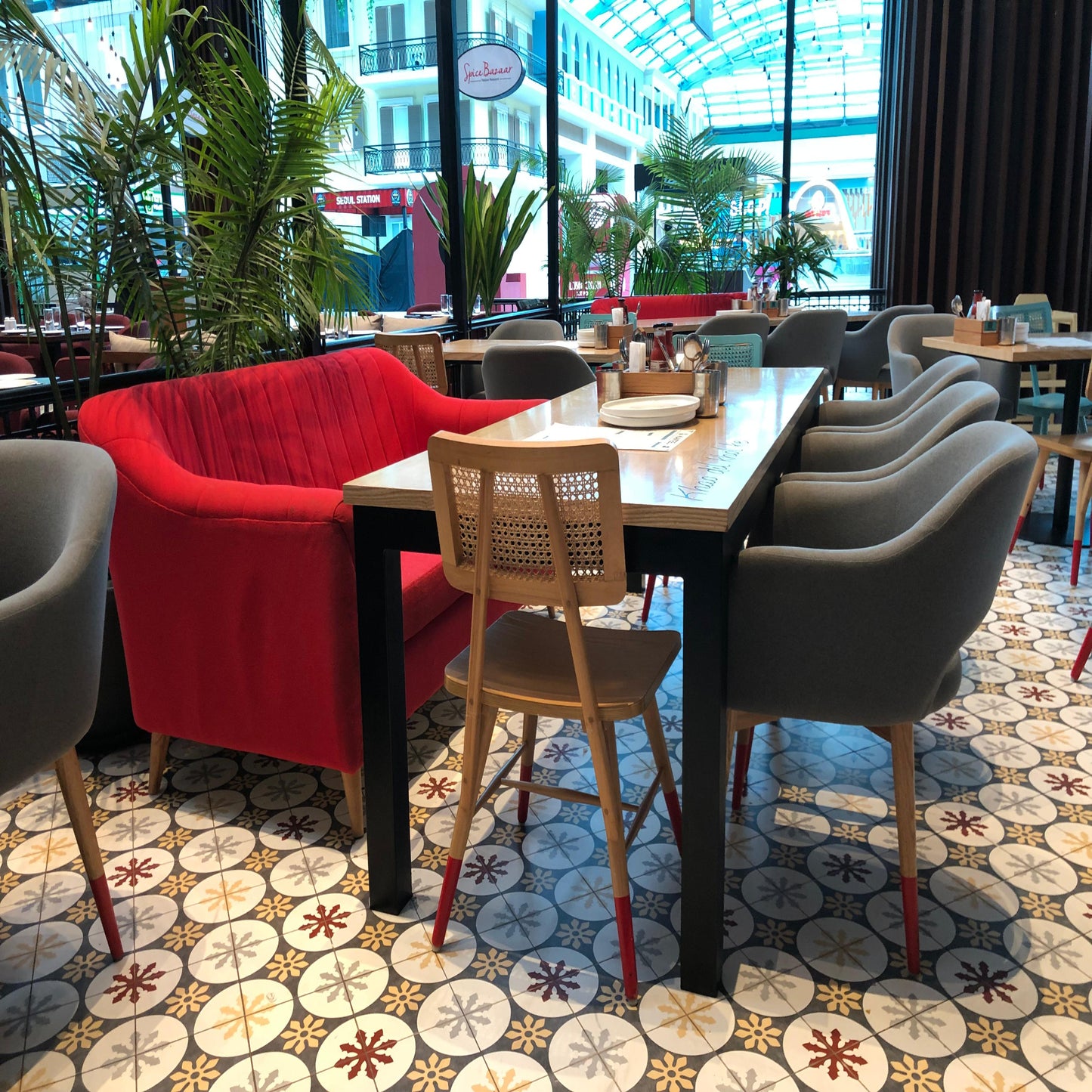Modern restaurant interior with red chairs, wooden table, and patterned floor.