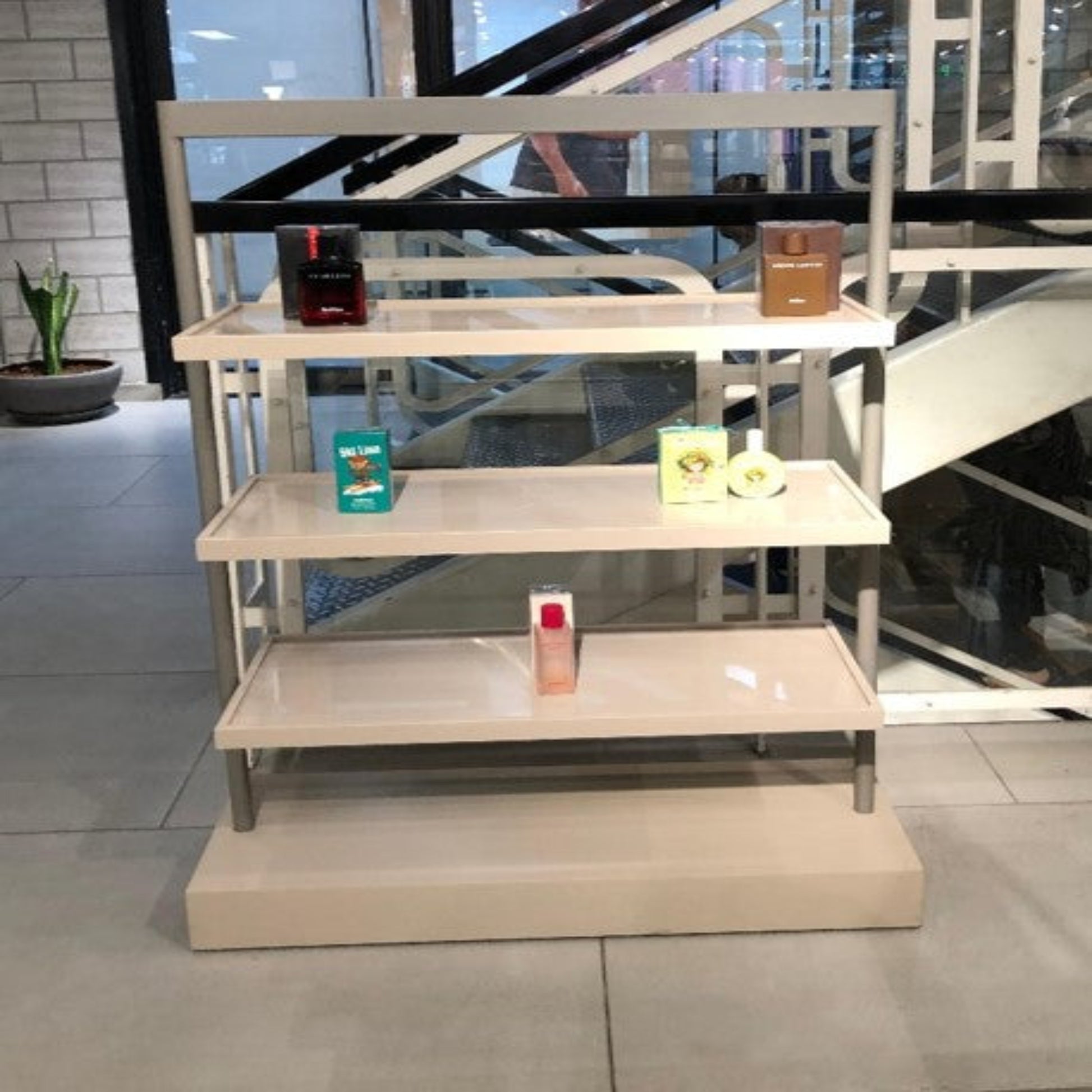 Beige display shelf with products against a staircase background