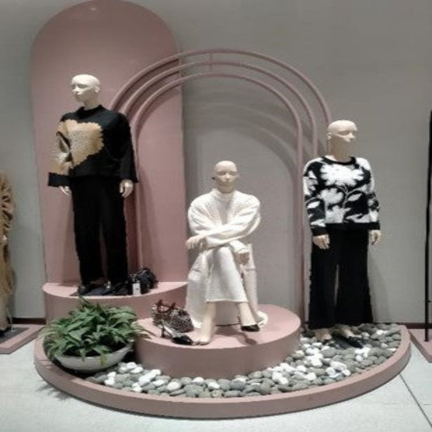 Mannequins dressed in stylish outfits in a display setting with decorative elements.