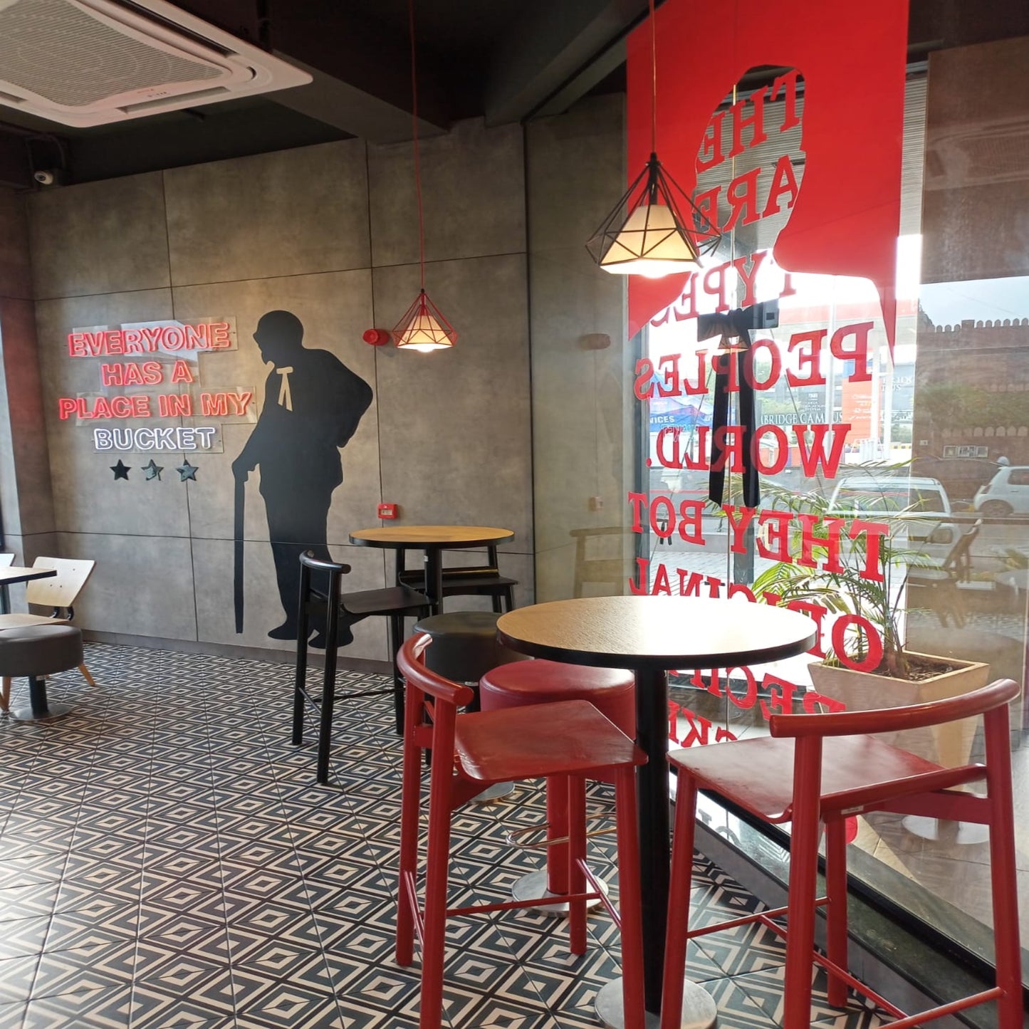Kfc Pakistan, modern cafe interior with red chairs, tables, and decorative wall art.