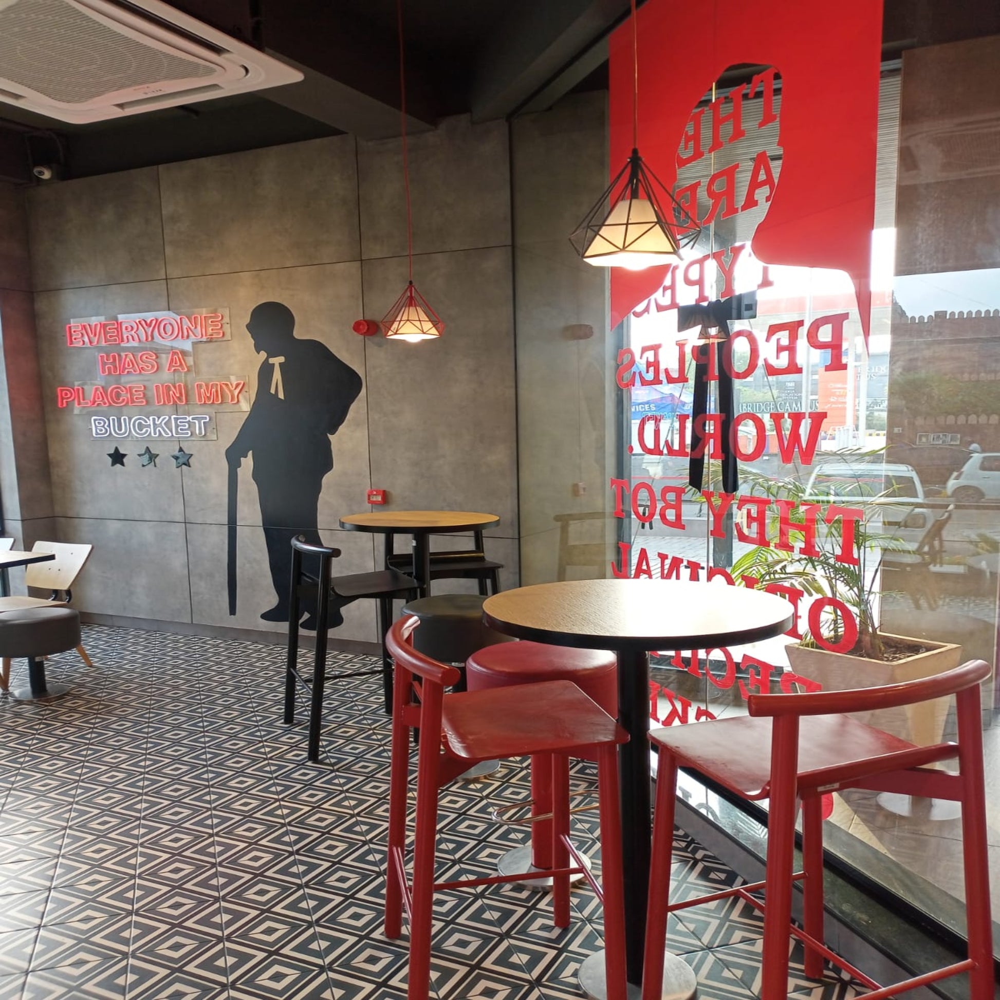 Kfc Pakistan, modern cafe interior with red chairs, tables, and decorative wall art.