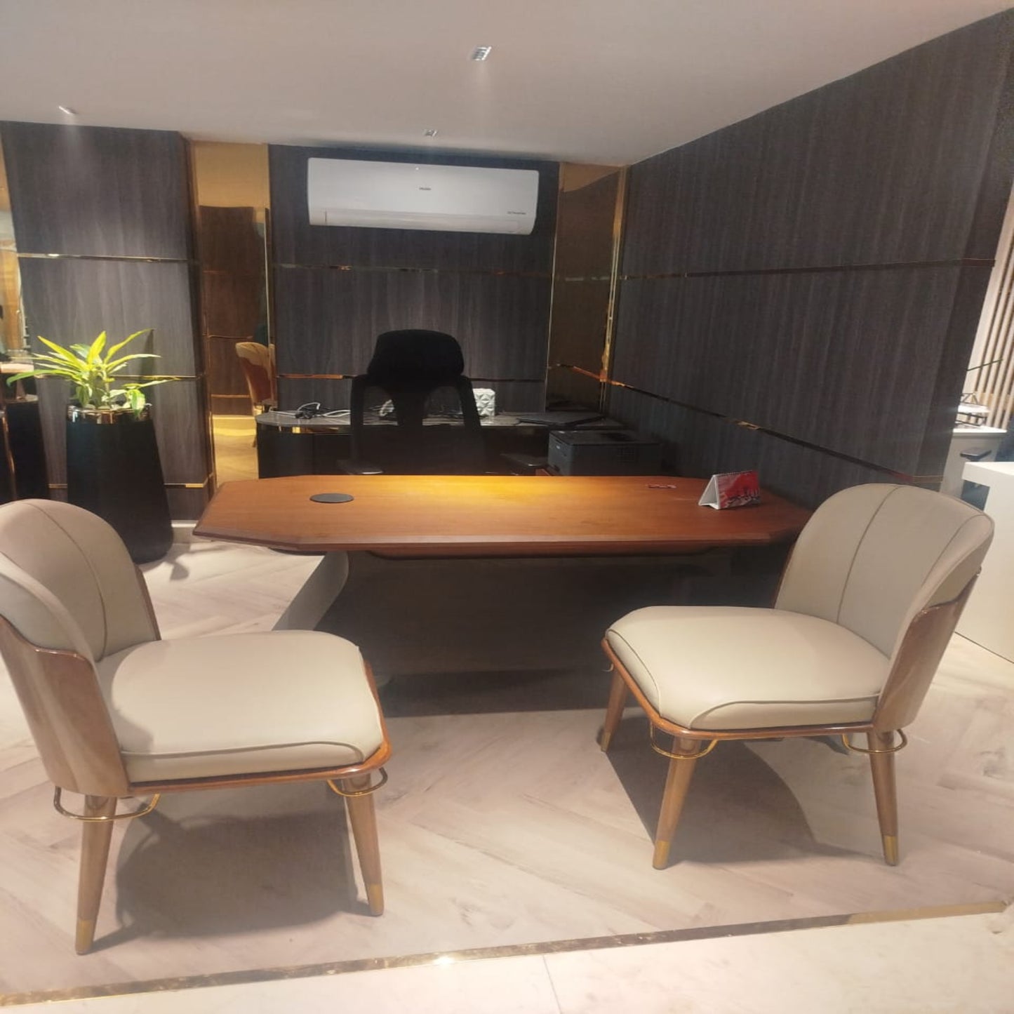 Modern office setup with a wooden desk and beige chairs in a well-lit room.