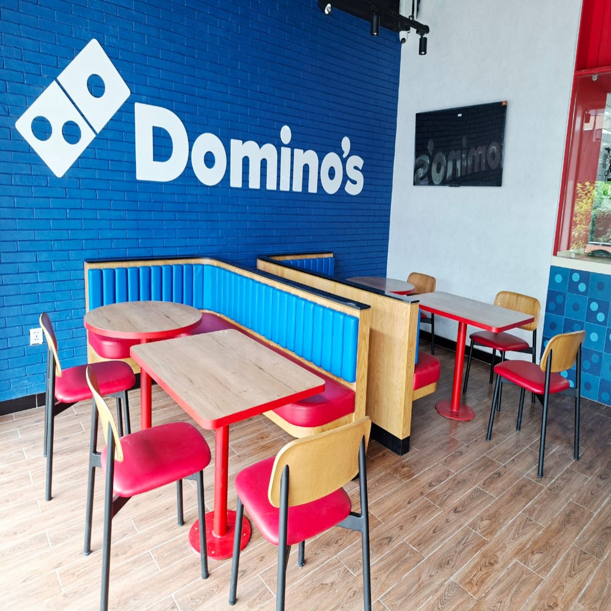 Domino's restaurant interior with tables, chairs, and blue wall with logo.