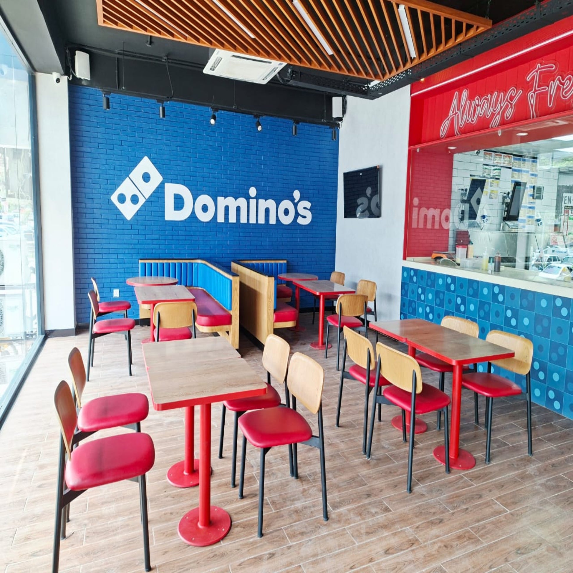 Domino's Pizza restaurant interior with tables, chairs, and branded walls.