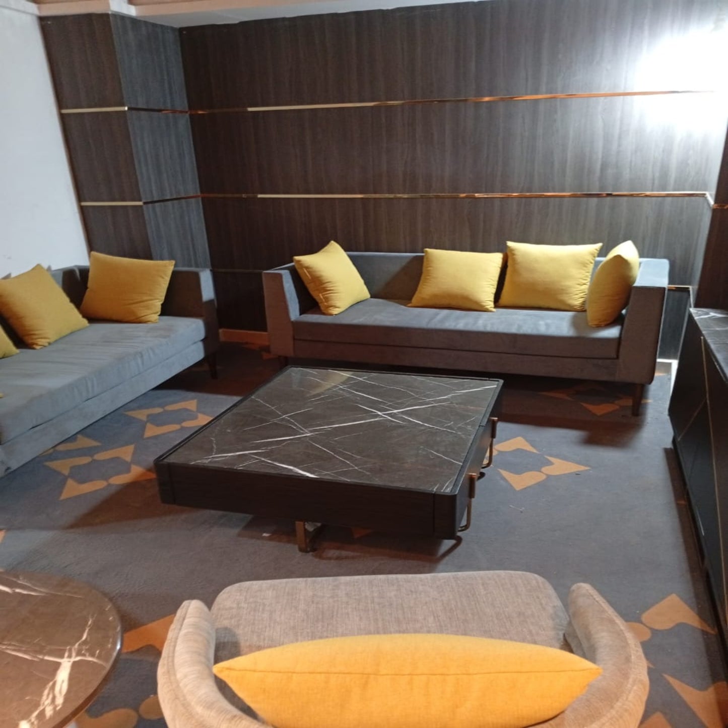 Modern seating room in bank with gray sofa, yellow cushions, and a marble coffee table.