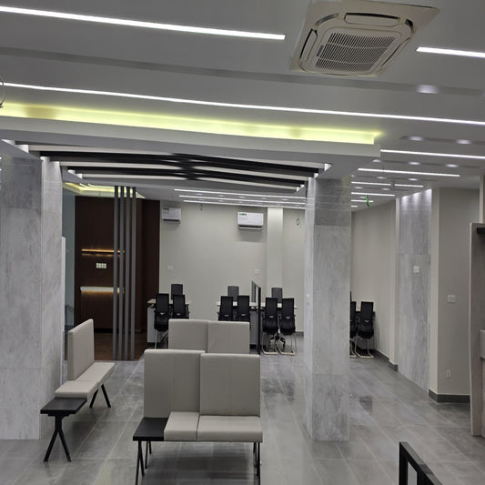 Modern office space with marble walls and floor, beige sofas, and office chairs.